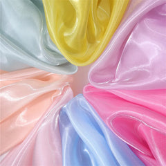 Close-up of Longan Craft’s Shiny Liquid Organza Fabric By The Yard, featuring pastel yellow, pink, blue, peach, and mint with a glossy finish arranged in folds—ideal for luxury evening wear or bridal gowns.